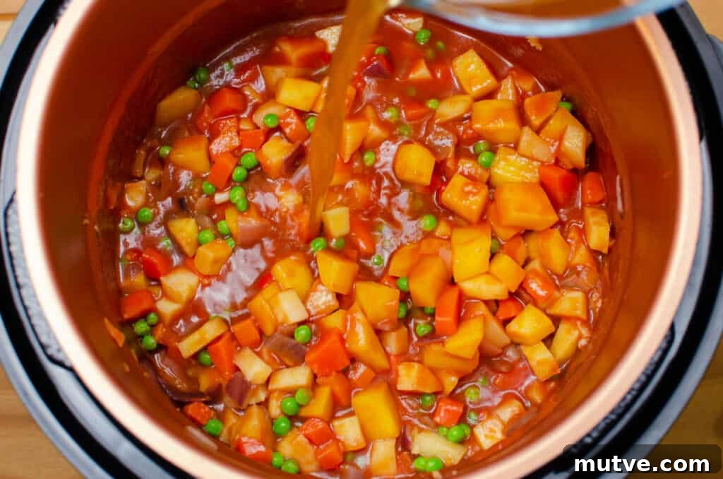 One-Pot Quinoa Vegetable Stew 9 Vegetable stock being poured into the pressure cooker pot with the Tomato passata, Frozen peas, chopped red chillies and Garlic added to chopped carrots, parsnip, swede and red onion