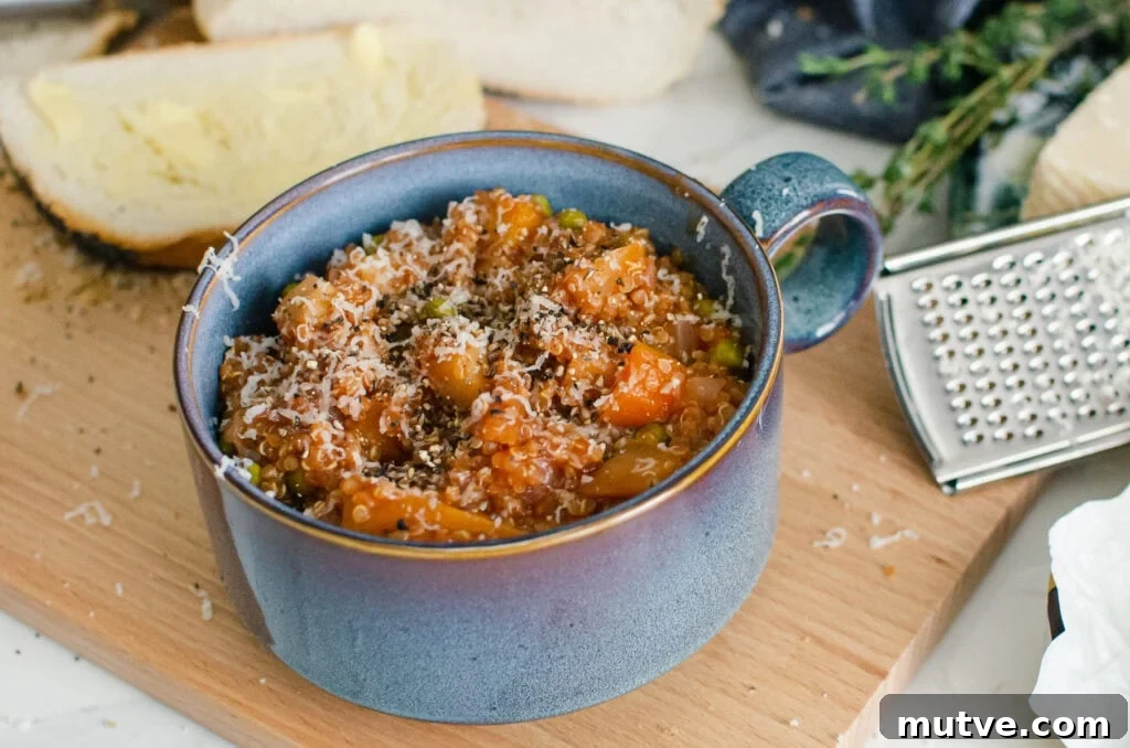 One-Pot Quinoa Vegetable Stew 13 Quinoa Vegetable Stew served in a blue bowl with sprinkled parmesan cheese on top with crusty bread and a silver grater on the side