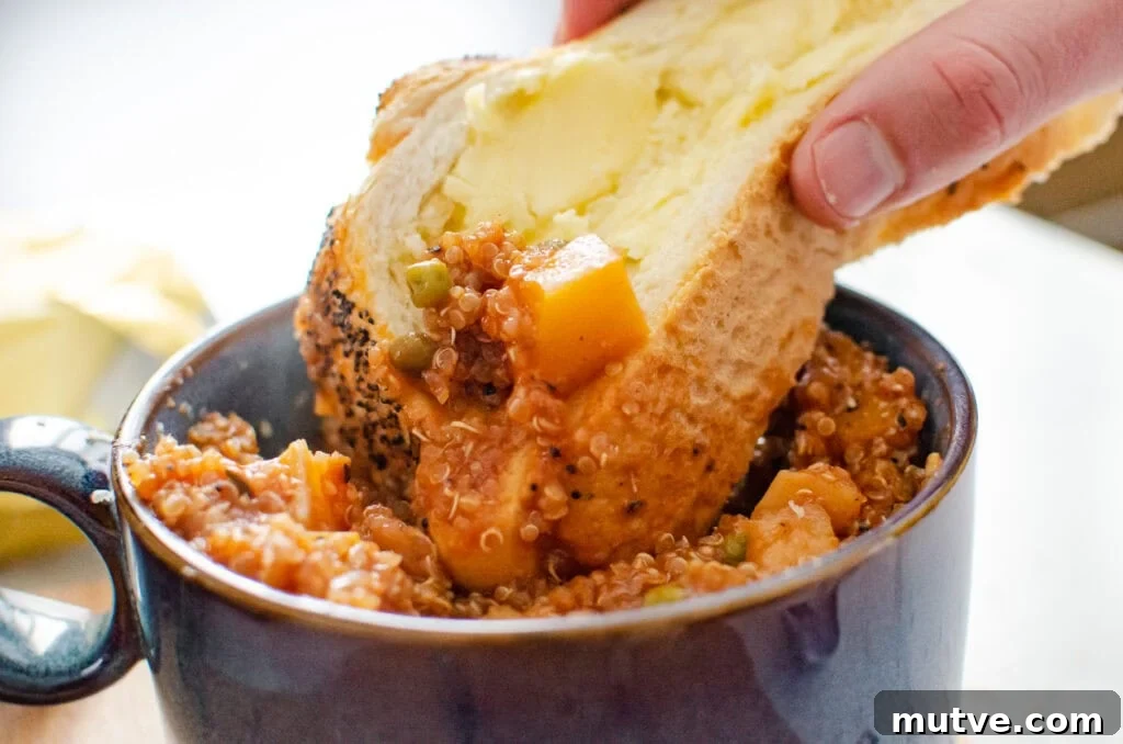 One-Pot Quinoa Vegetable Stew 14 Crusty bread being dipped into vegetable stew in a blue bowl on a bread board