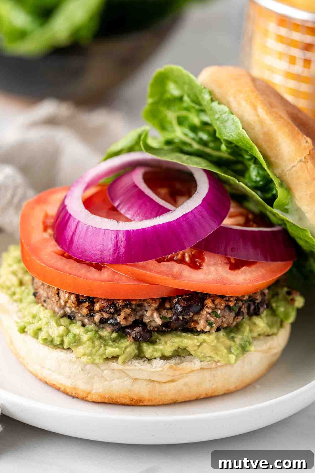 Sliced red onion and tomato on top of the vegan black bean burger.