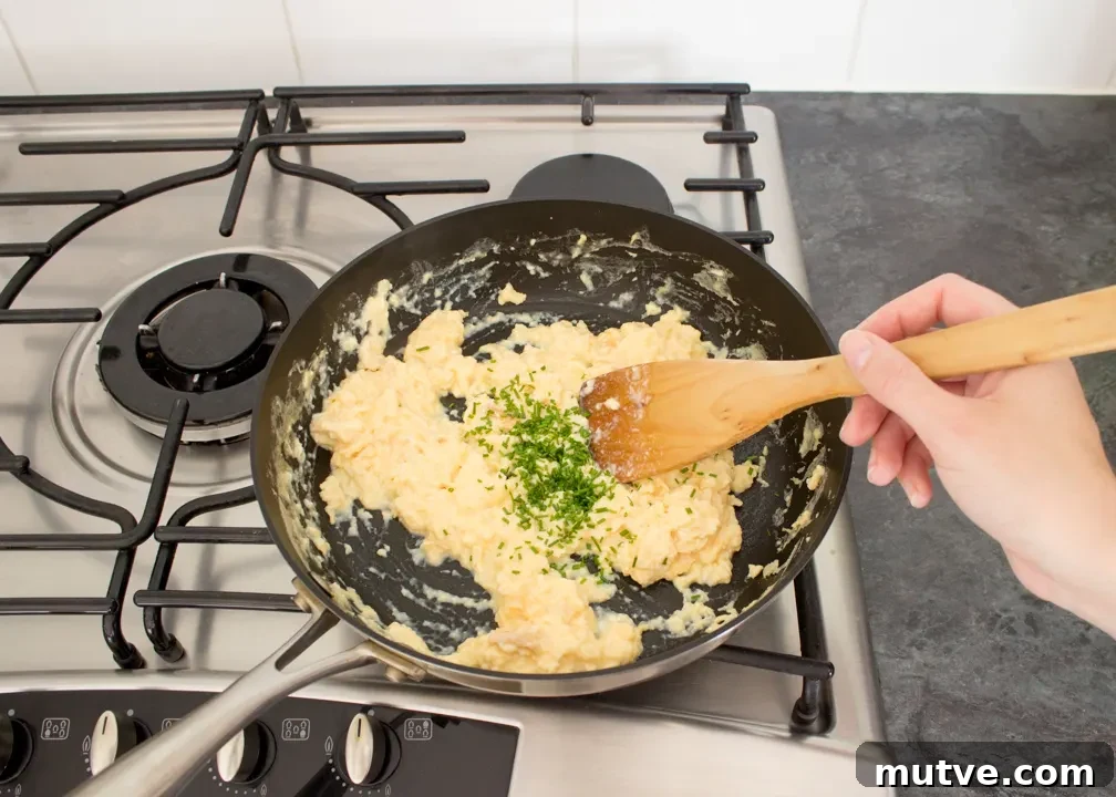 Cheese and Chive Scrambled Egg Croissant Recipe 6 Chives being mixed through scrambled eggs in a frying pan.