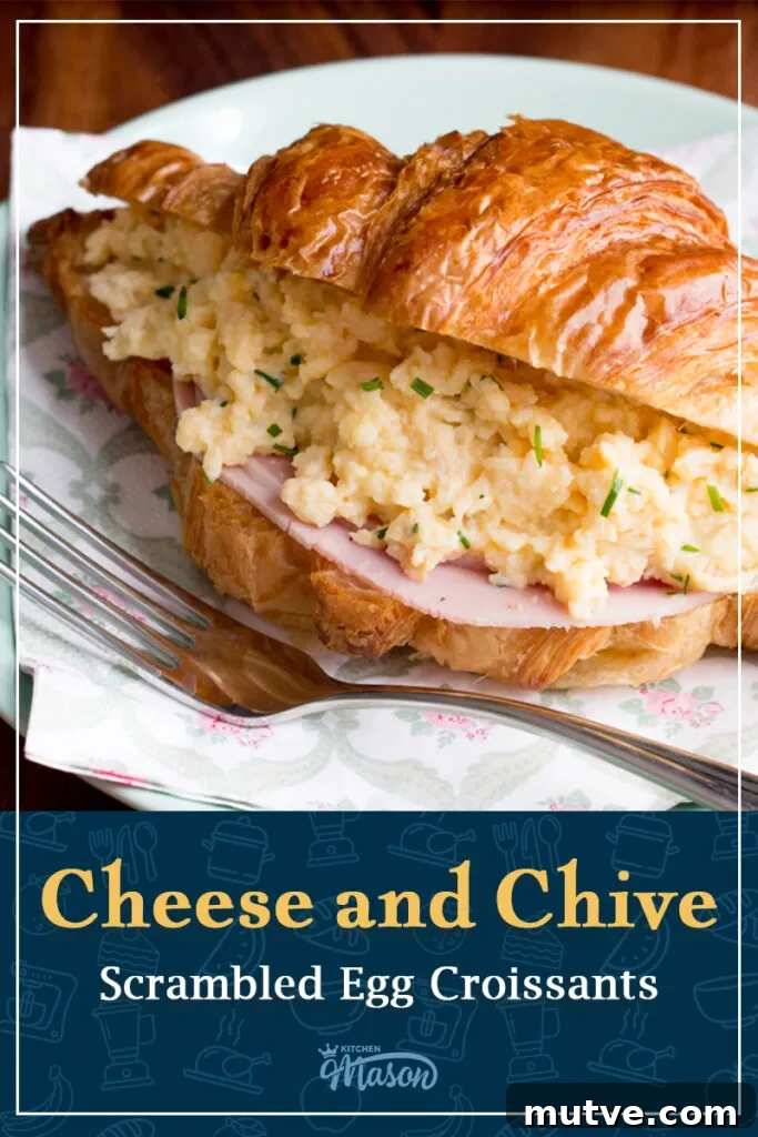 Cheese and Chive Scrambled Egg Croissant Recipe 9 A cheese and chive scrambled egg croissant on a plate with a napkin and fork. A text overlay says "Cheese and Chive Scrambled Egg Croissants".