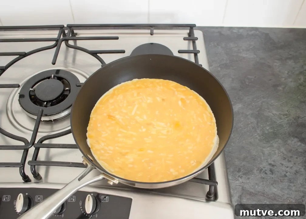 Cheesy egg mixture cooking in a frying pan.