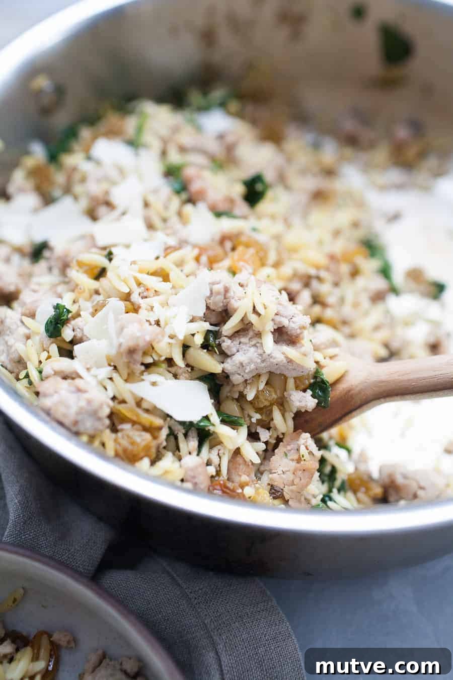 One-Pot Ground Turkey Pasta Recipe 2 A pan full of spinach and turkey with a wooden spoon.