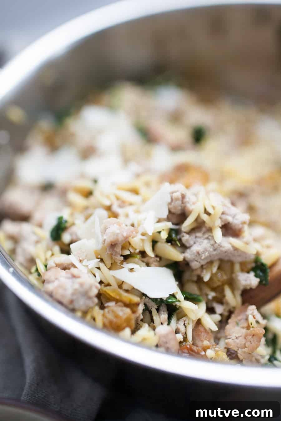 One-Pot Ground Turkey Pasta Recipe 4 A skillet full of turkey and spinach with a wooden spoon.