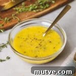 A close-up of lemon thyme vinaigrette in a glass bowl with a spoon inside.