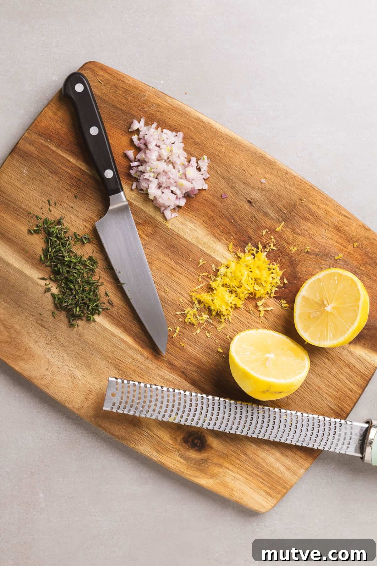 Ingredients like lemon, shallot, and thyme getting prepped on a cutting board.