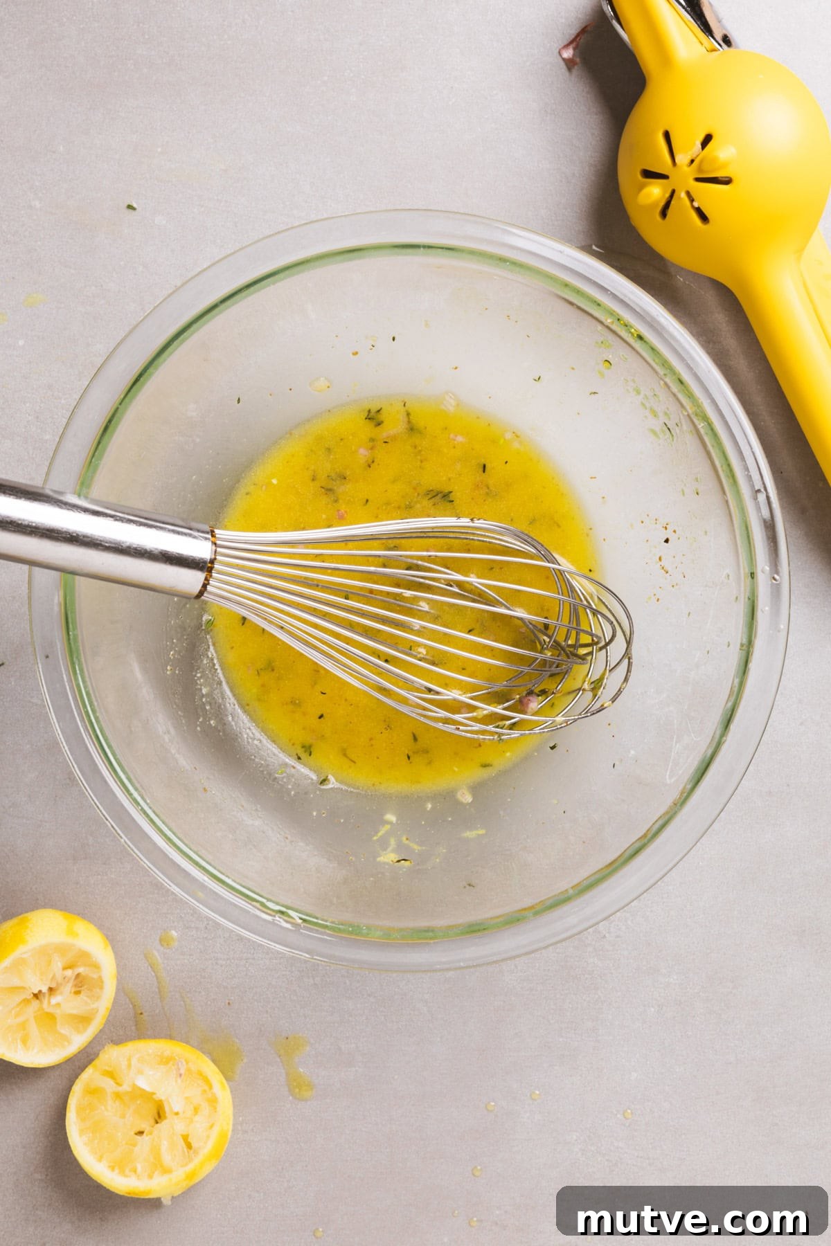 Lemon thyme vinaigrette getting whisked together in a medium glass bowl.