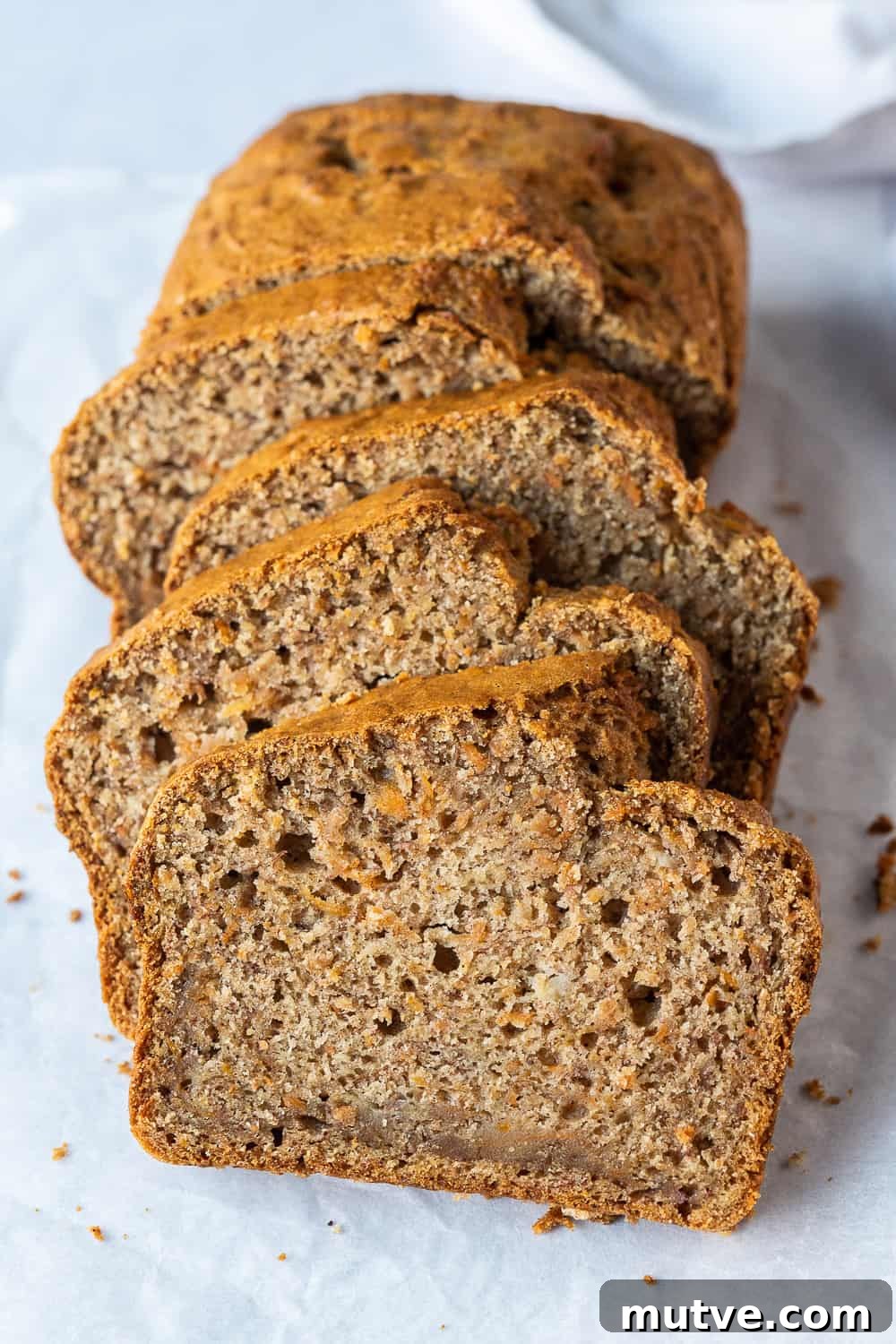 Loaf of carrot banana bread on a grey background.