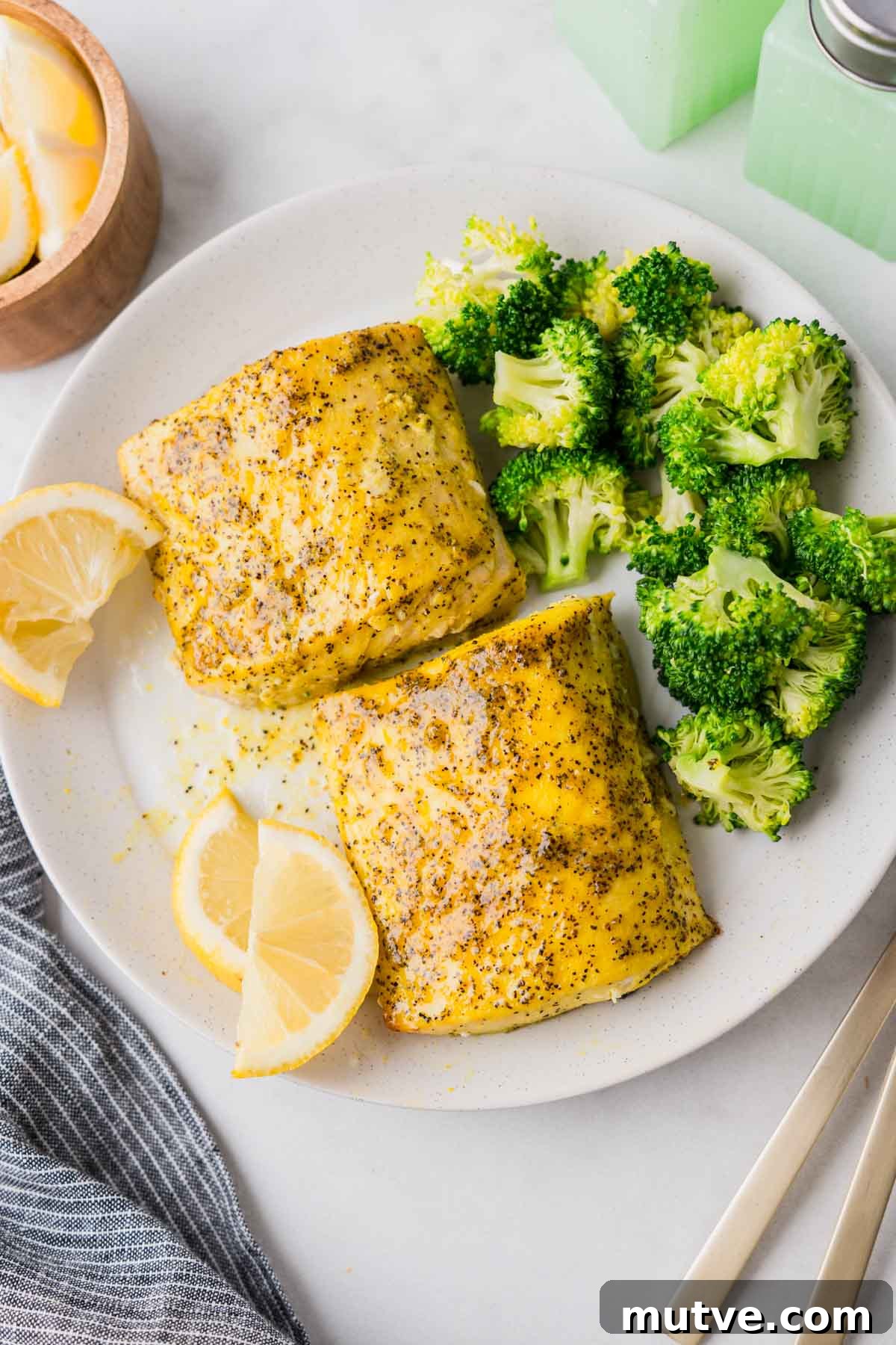 Crispy Air Fryer Mahi Mahi Recipe 2 air fryer mahi mahi with broccoli and lemon wedges on a white plate.