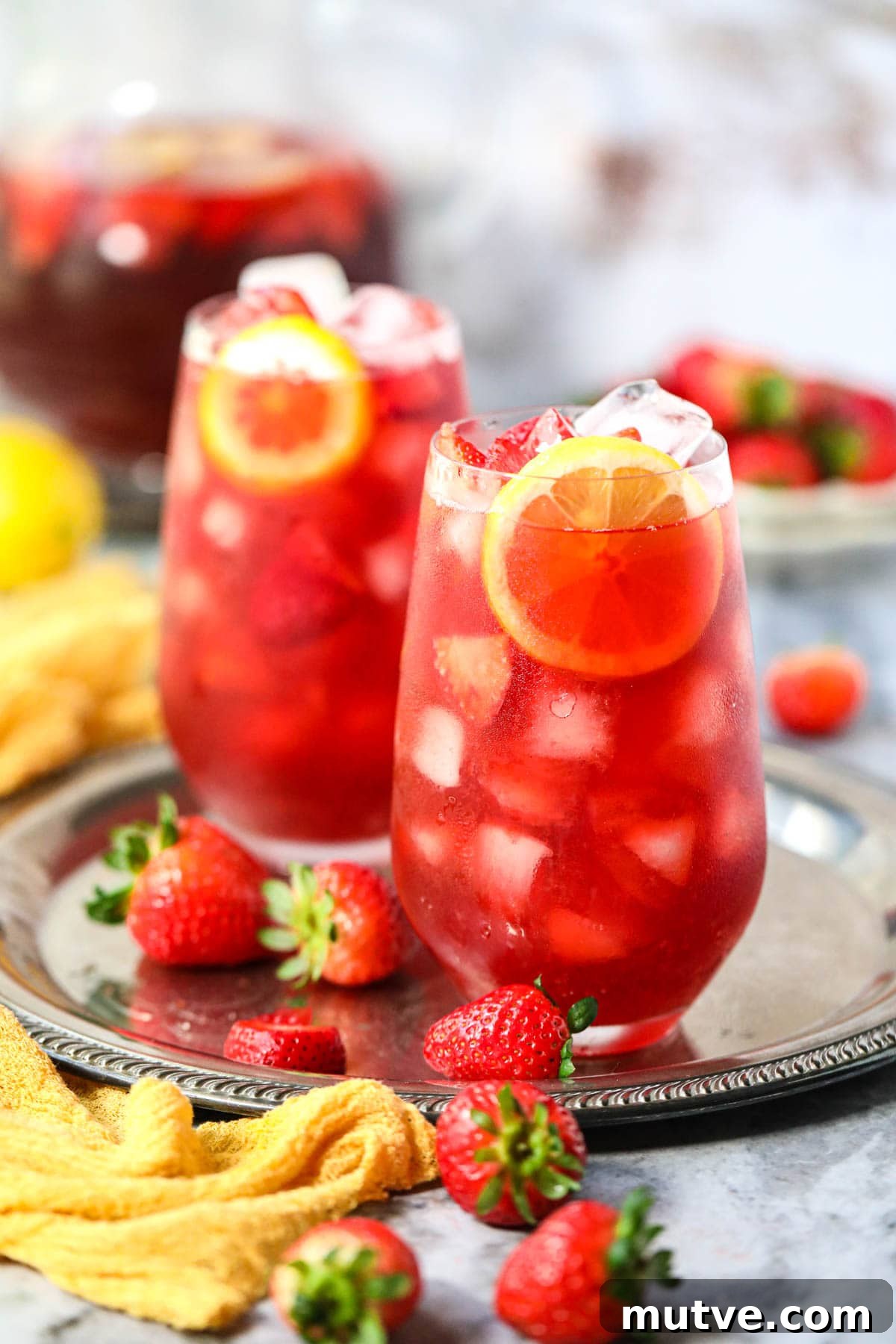 Strawberry sweet iced tea and clear glasses sitting on a metal tray.