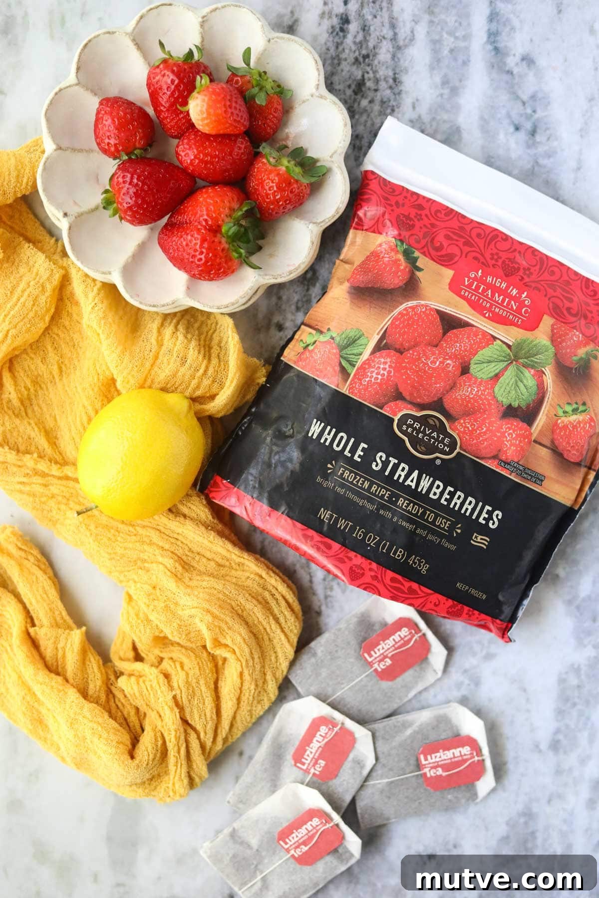 Ingredients for making strawberry sweet ice tea on a gray surface.