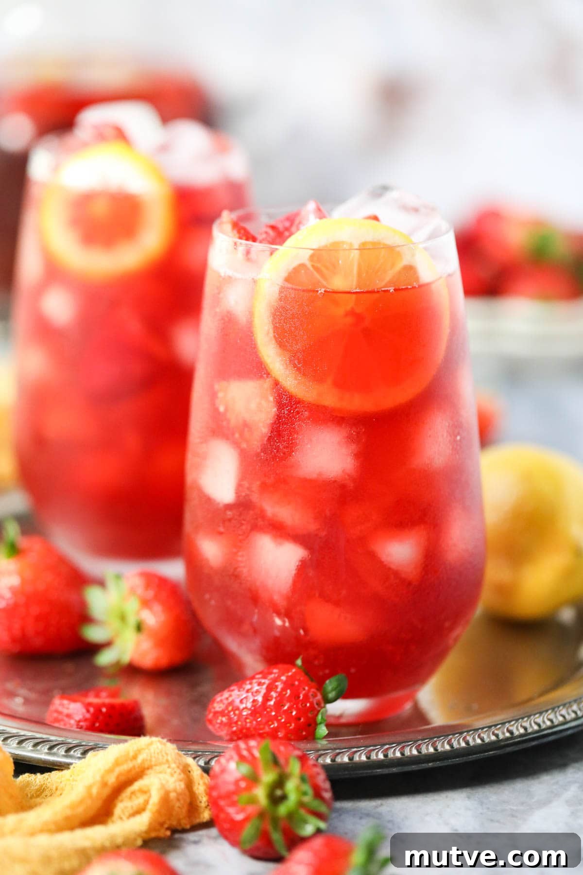 Strawberry sweet iced tea in tall glasses on a metal serving tray.