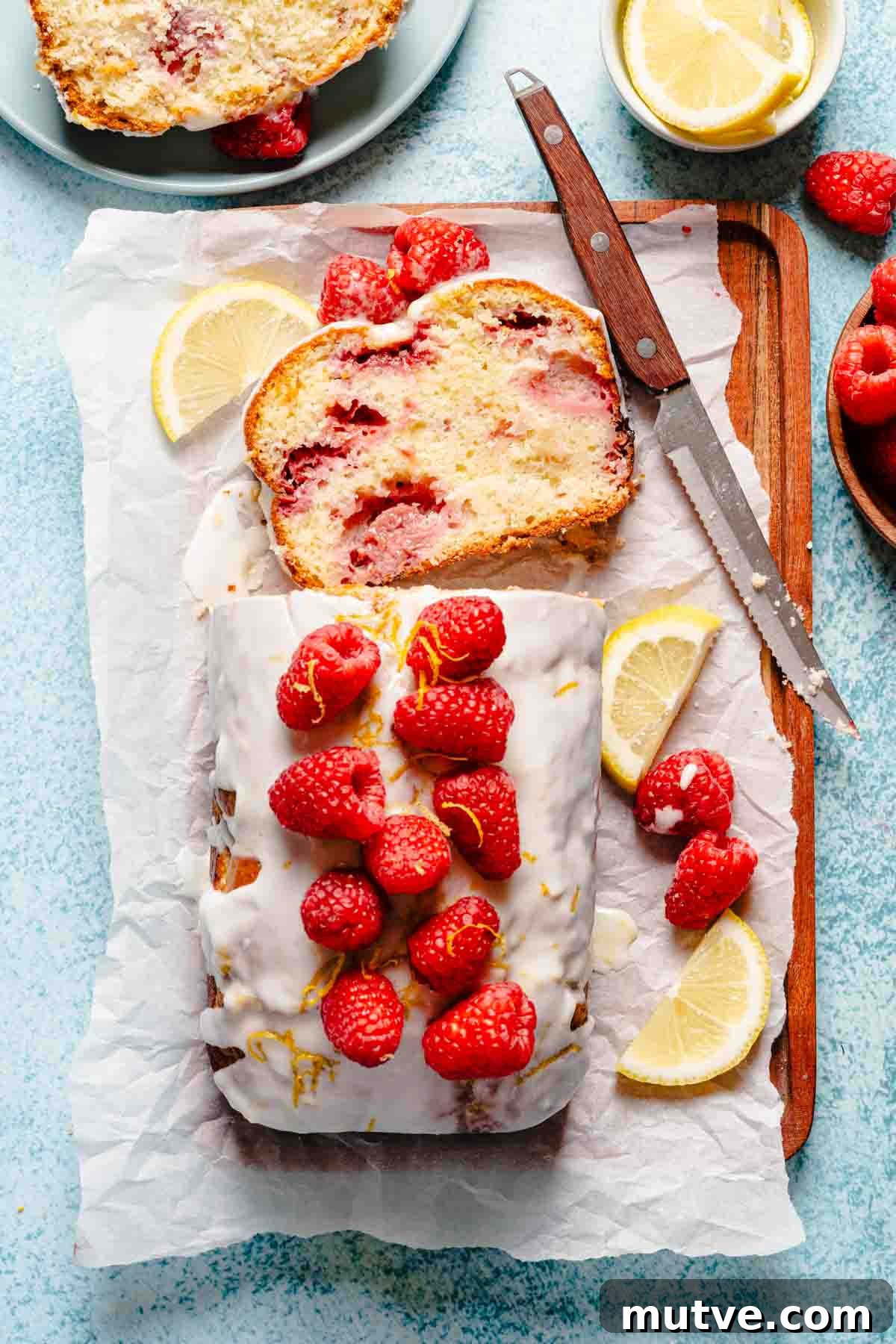 raspberry loaf cake garnished with raspberries and lemon slices.