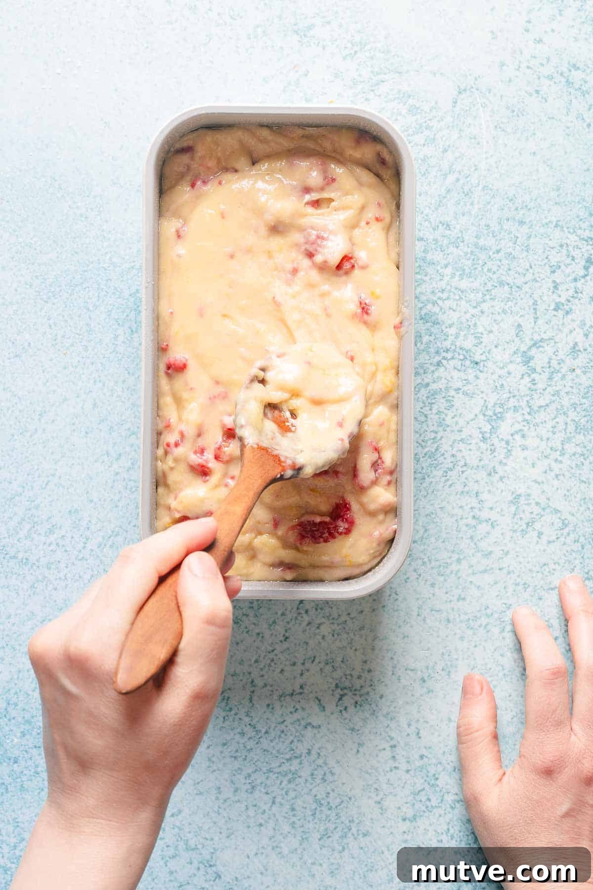 raspberry loaf cake batter being spread out in loaf pan.