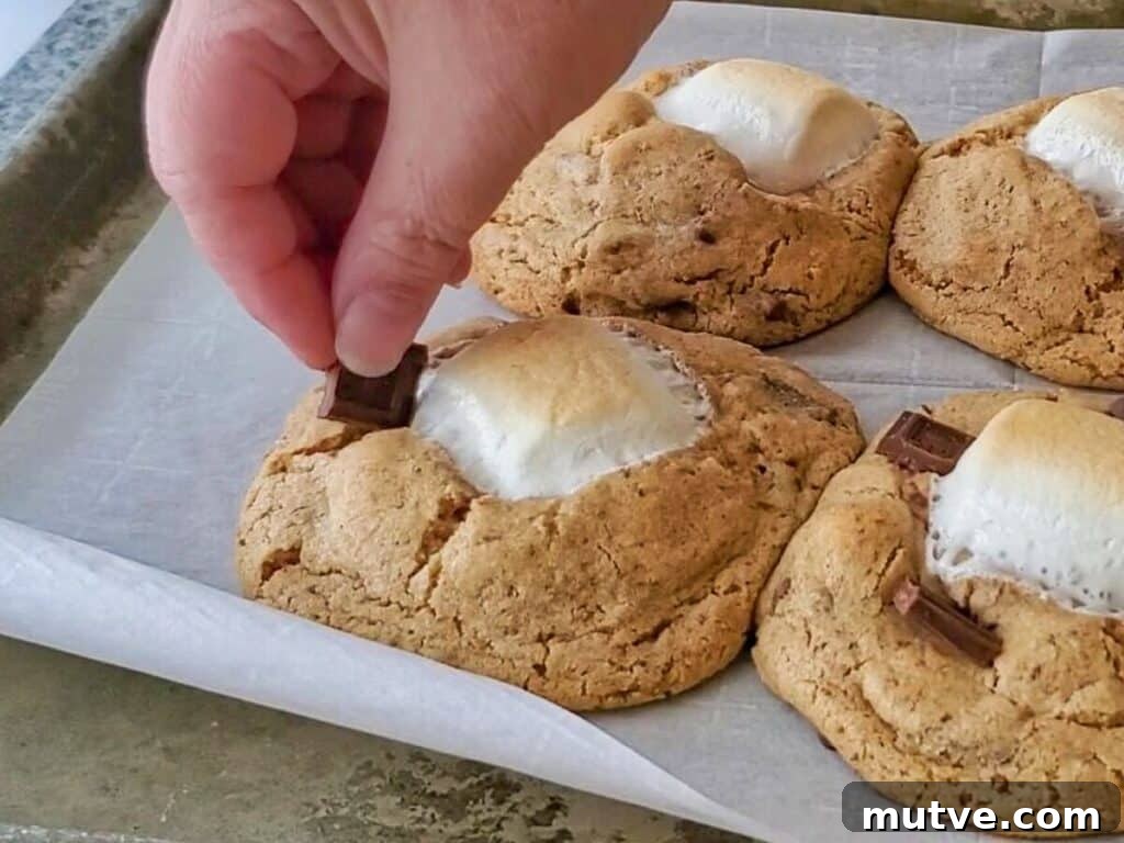 Gluten-Free Smores Cookies with Gooey Marshmallow and Chocolate 11 pushing chocolate pieces into warm cookies after baked.