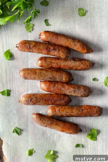 Air fryer sausages placed on parchment paper with a bunch of cilantro in the background.
