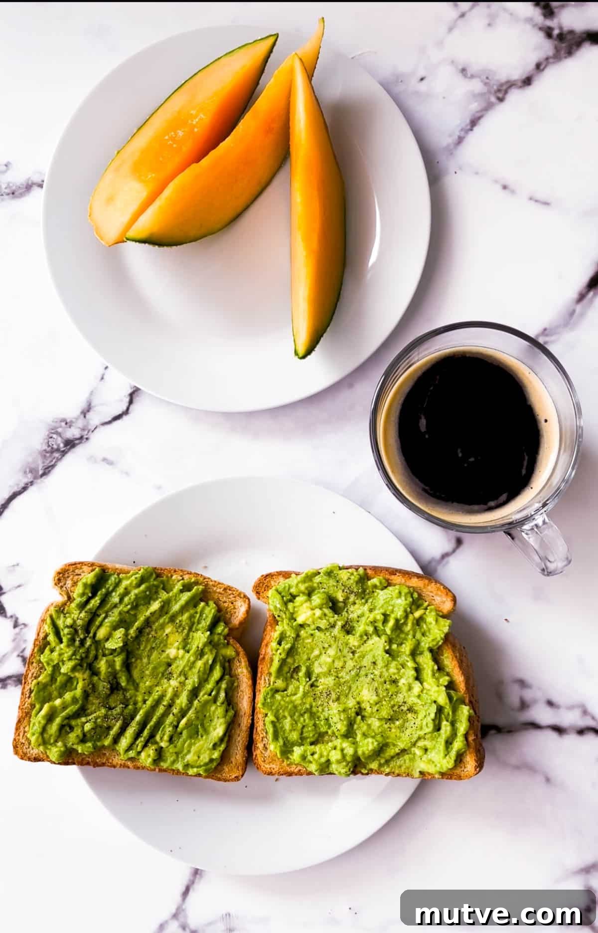 A closeup of avocado toast with cantaloupe slices and a mug of coffee.