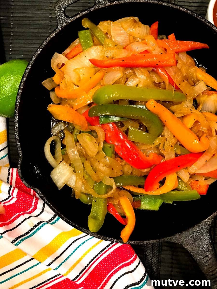 Sizzling Tex-Mex Fajitas Recipe with Peppers and Onions 5 Sliced red, yellow and green bell peppers and onions in cast iron skillet.