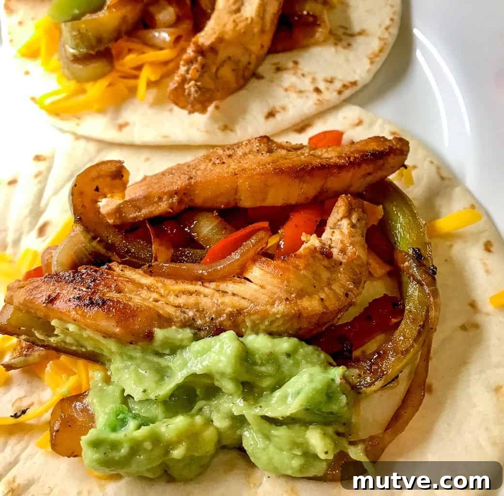 Sizzling Tex-Mex Fajitas Recipe with Peppers and Onions 8 Tex Mex chicken fajitas open faced on a white plate.
