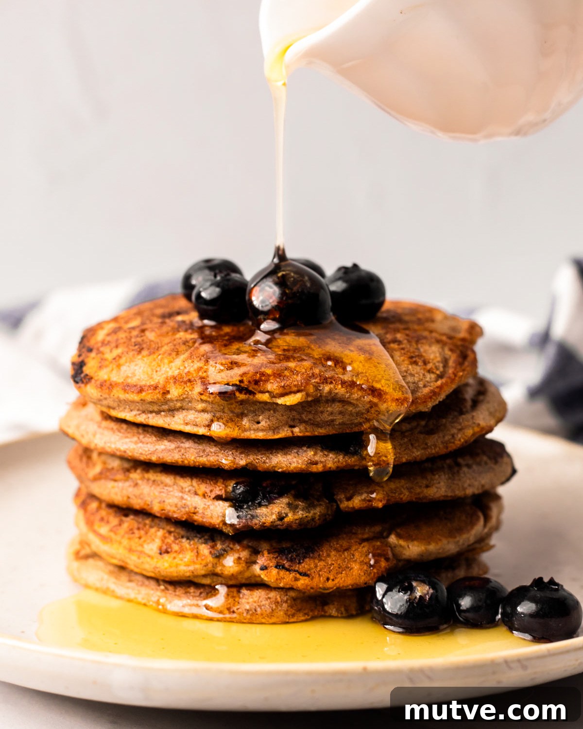 50 Vegan Brunch Recipes to Impress Guests 3 Drizzling a stack of the vegan blueberry pancakes with maple syrup.