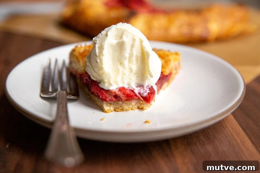 Slice of strawberry galette with ice cream on a plate with bite taken out.
