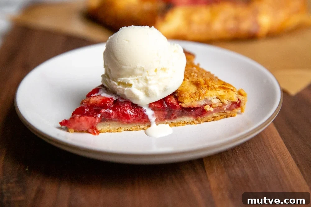 A slice of strawberry galette topped with a scoop of vanilla ice cream.