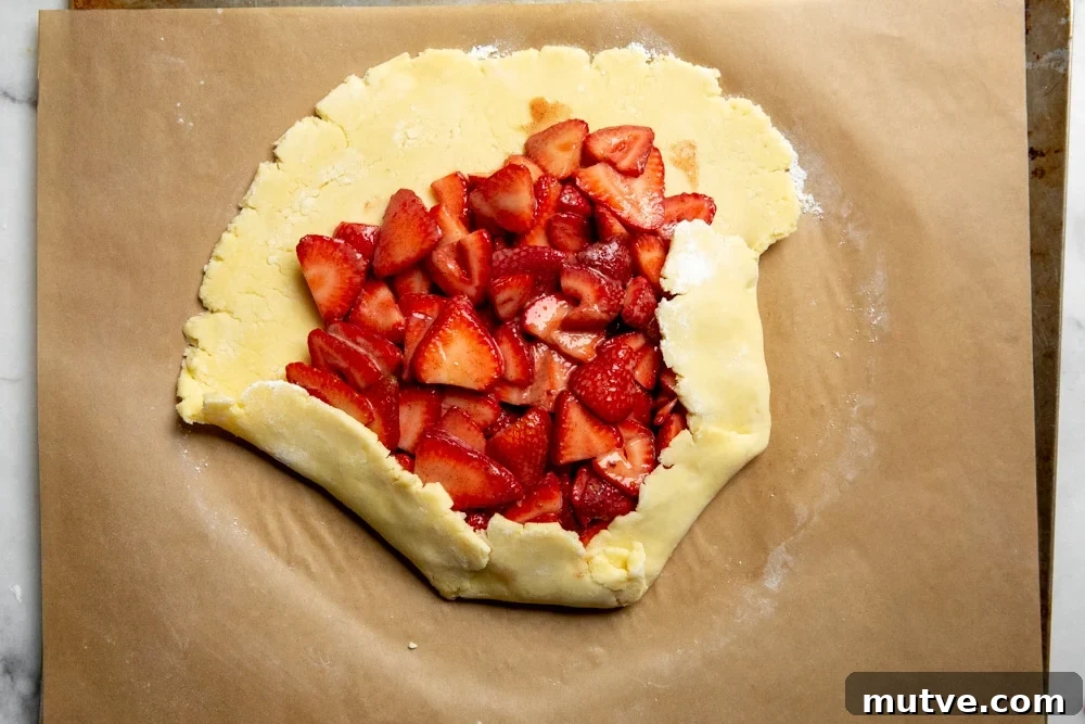 Process shot showing how to fold up the pie dough for the strawberry galette recipe.