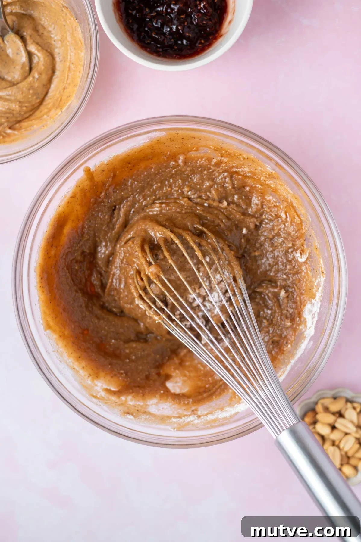 cake batter in a bowl with a whisk with half the flour added