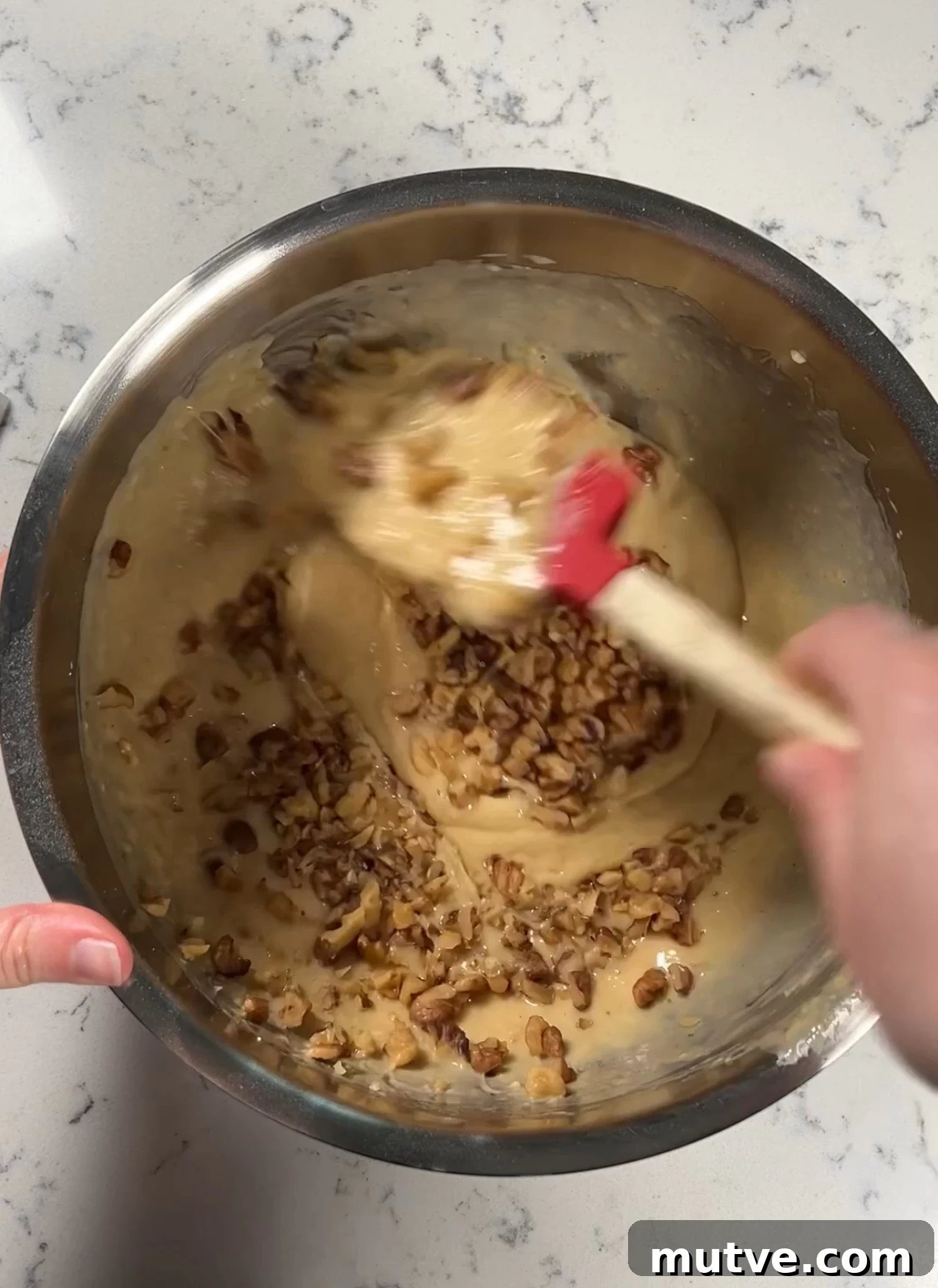 Adding in walnut pieces to the cake batter.