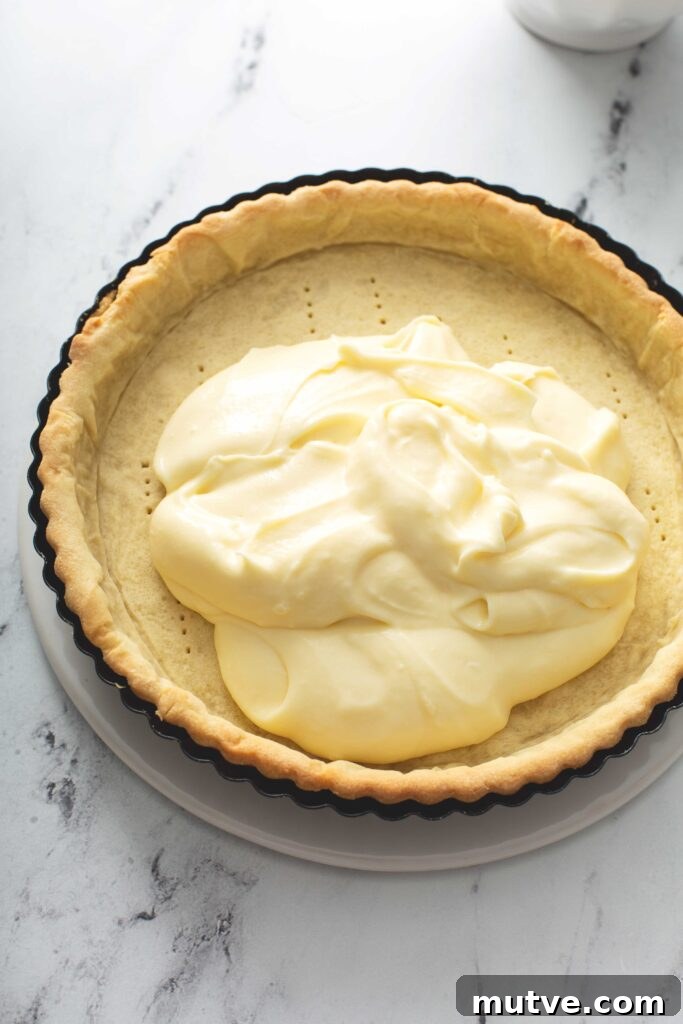 How to Make a Fresh Fruit Tart with Vanilla Custard 9 A baked golden brown pastry tart crust getting topped with vanilla pastry cream.