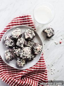 Chocolate Cake Cookies with White Chocolate Peppermint Sprinkle Chocolate Cake Cookies on a marble counter with a red towel and glass of milk.