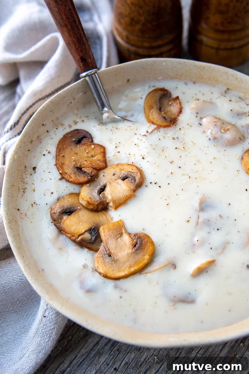 Gluten-Free Cream of Mushroom Soup Recipe 2 a spoon going into a bowl of gluten free mushroom soup with sauteed mushrooms on top