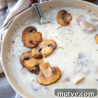 Gluten-Free Cream of Mushroom Soup Recipe 8 a spoon going into a bowl of gluten free mushroom soup with sauteed mushrooms on top