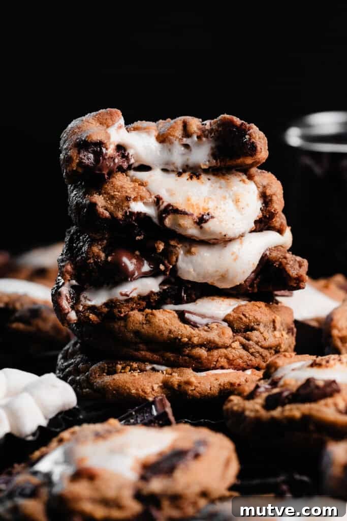A tall stack of s'mores cookie halves, with gooey marshmallow centers oozing out.
