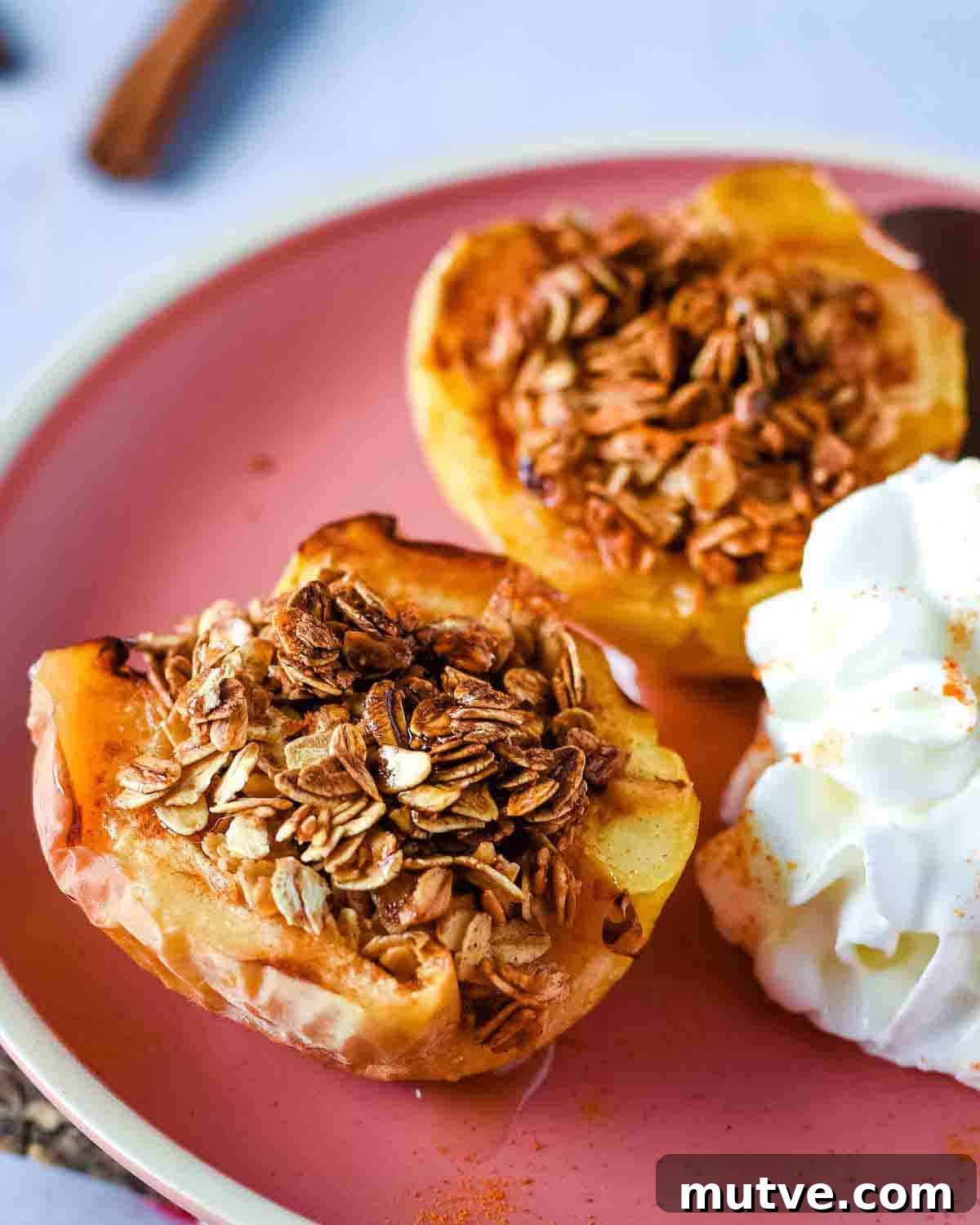 How to Cook With and Store Cinnamon 3 Air fryer baked apples are shown on a pink plate with whipped cream.