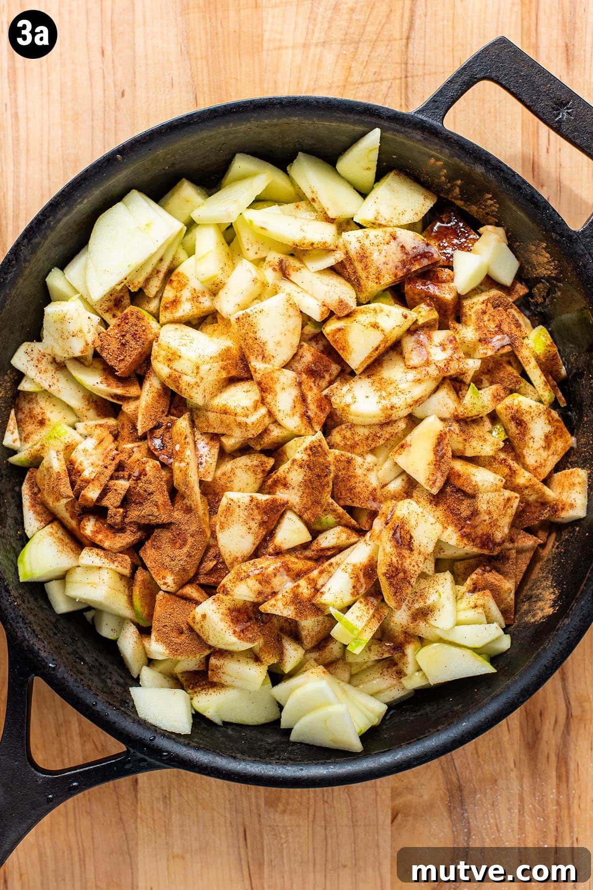 Skillet Apple Crisp Recipe with Cinnamon Oat Topping 5 Sliced granny smith apples in a cast iron skillet topped with ground cinnamon, nutmeg, and melted butter.