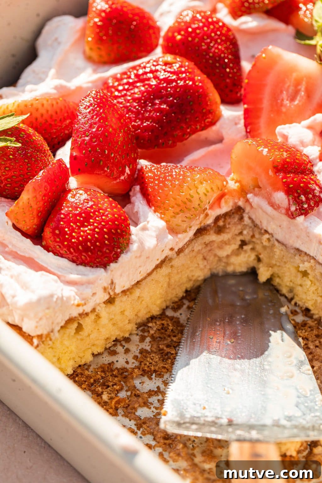 Strawberry Tres Leches Cake Recipe 10 strawberries on top of the cake with a slice cut out of it