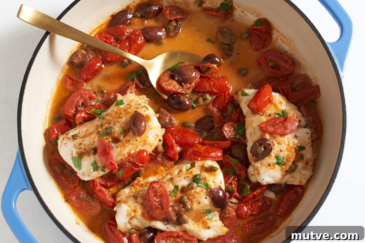 One-Pan Puttanesca Fish Recipe 7 Fish puttanesca in a skillet with blue handles, a gold spoon is in the sauce.
