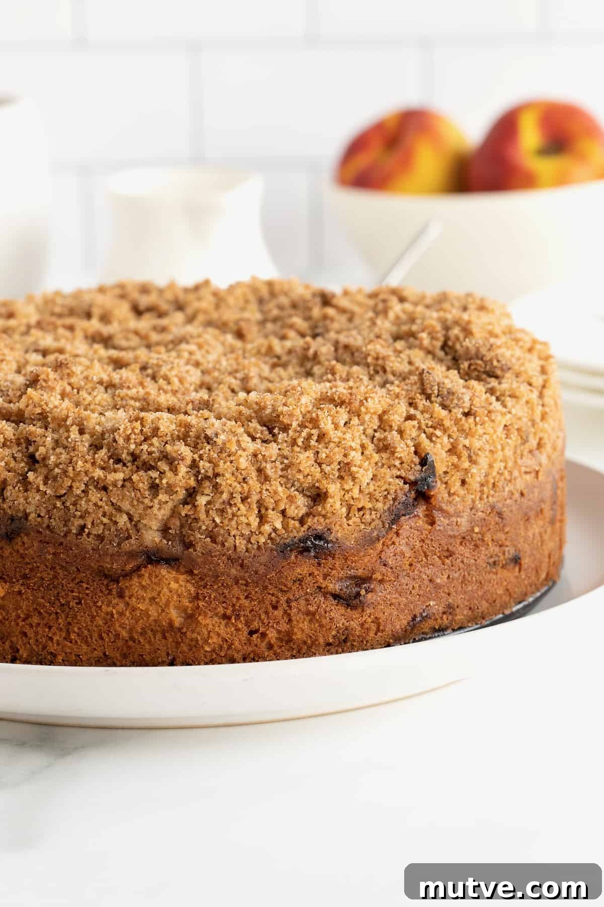 Peach Coffee Cake with Cinnamon Streusel 3 A peach coffee cake with cinnamon sugar streusel on a white serving platter.