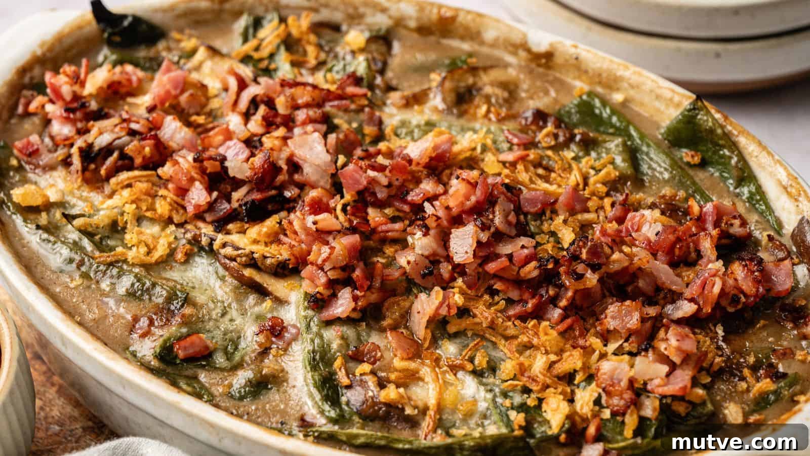 A baked casserole topped with chopped bacon, crispy onions, and melted cheese, featuring visible green peppers and a creamy sauce.
