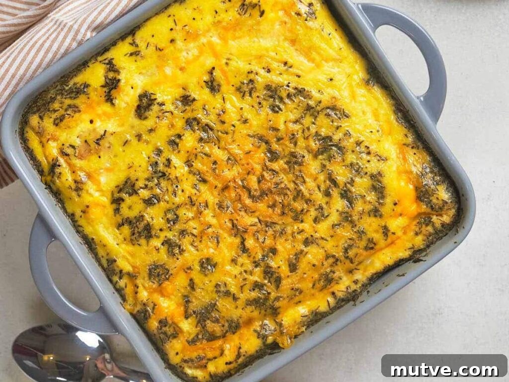 Breakfast casserole with a golden, cheesy top and sprinkled herbs in a square gray baking dish.