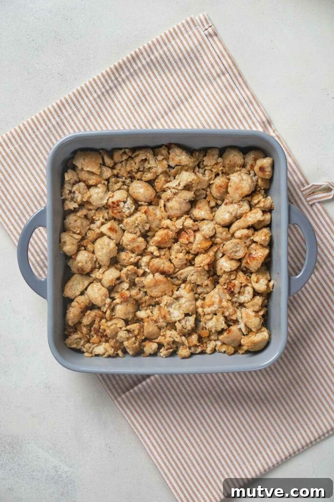 A blue square baking dish filled with crumbled, cooked pieces of textured protein.