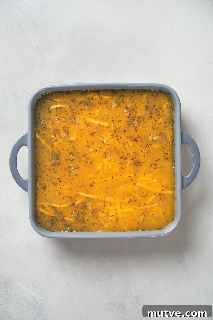 A square baking dish filled with egg mixture for breakfast casserole.
