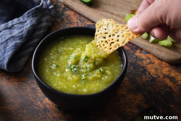 Cheese chip dipped into green tomato salsa verde