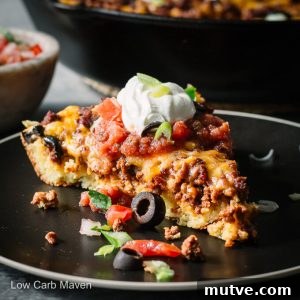 A slice of taco pie (taco bake) on a plate with Mexican seasoned ground beef baked into a cornbread crust.