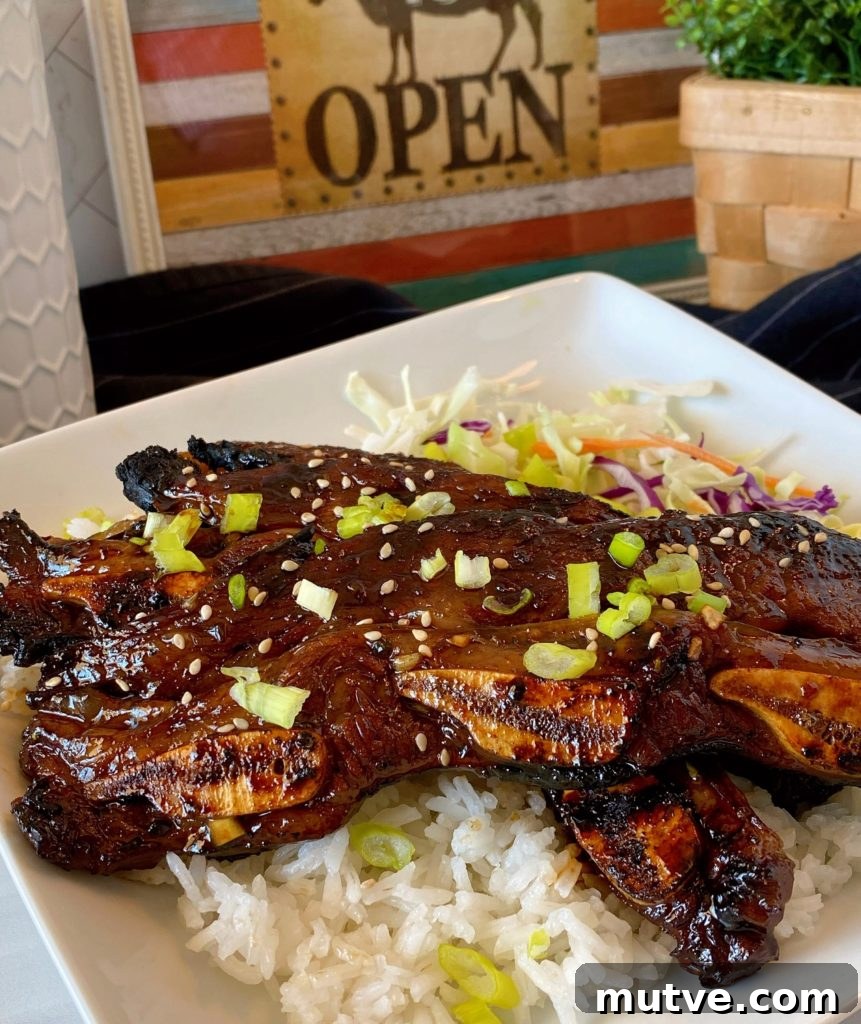 Hawaiian-Style Kalbi Grilled Beef Short Ribs on a white plate on top of white rice with cabbage.