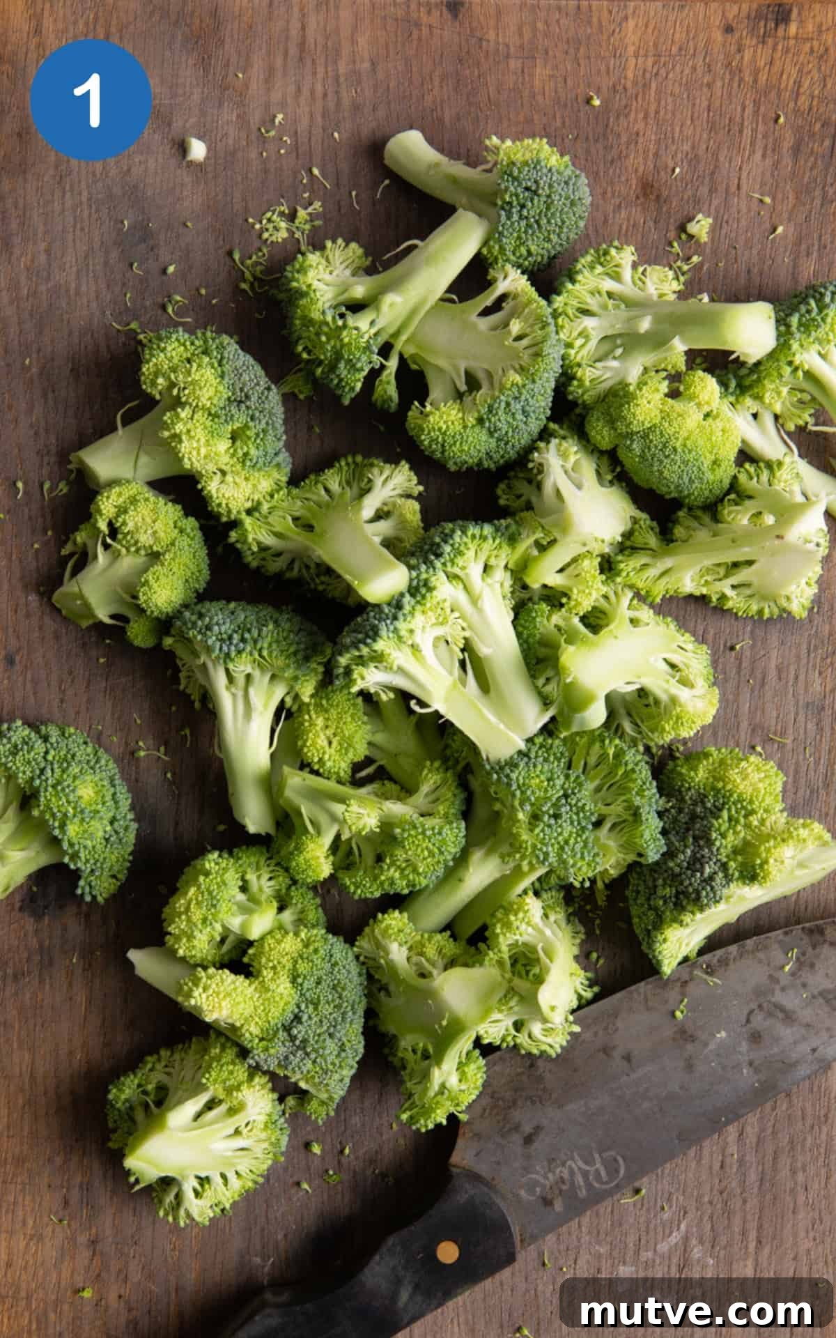 Crispy Air Fryer Broccoli in 10 Minutes 4 Broccoli chopped on dark wooden chopping board.