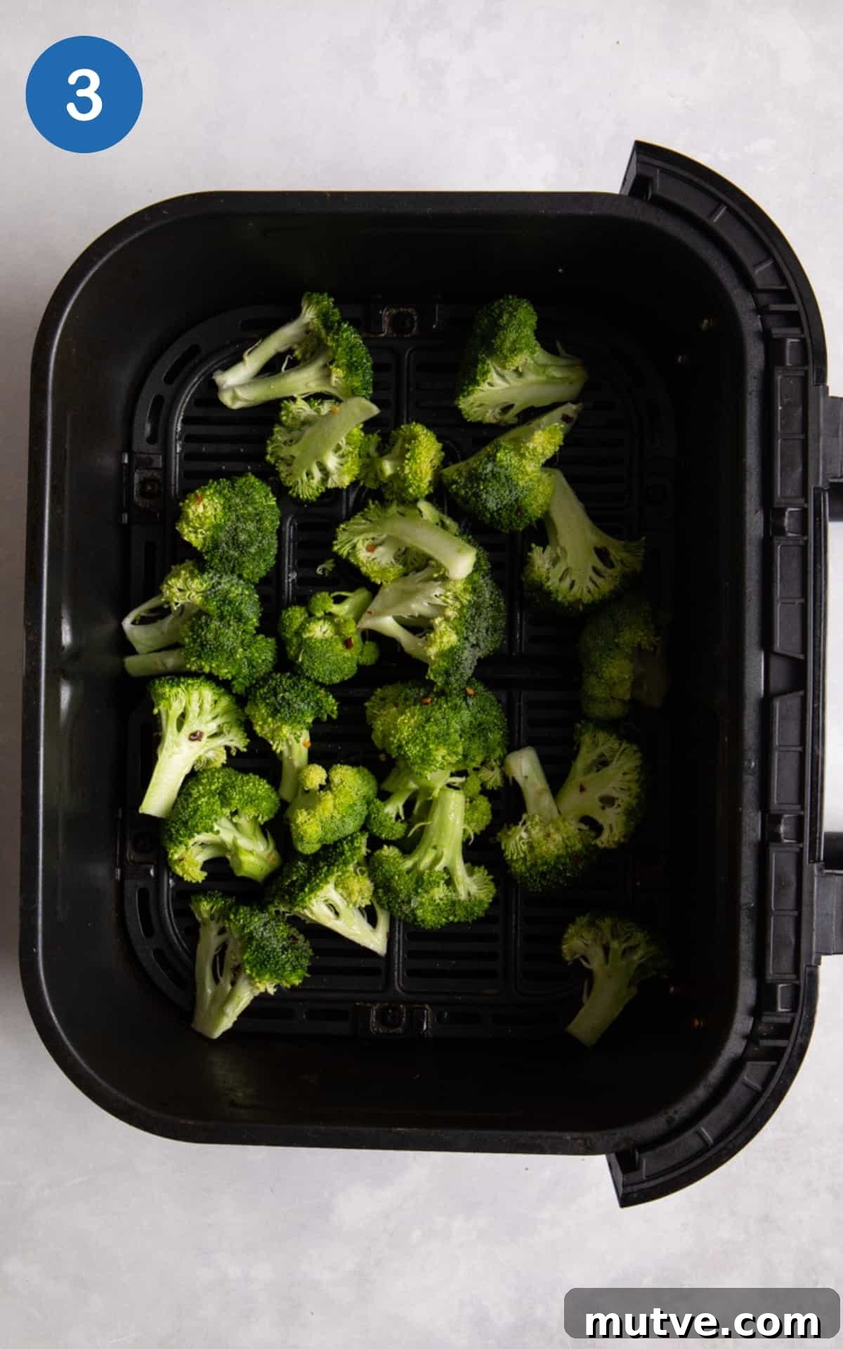Crispy Air Fryer Broccoli in 10 Minutes 6 Broccoli in black air fryer before being cooked.