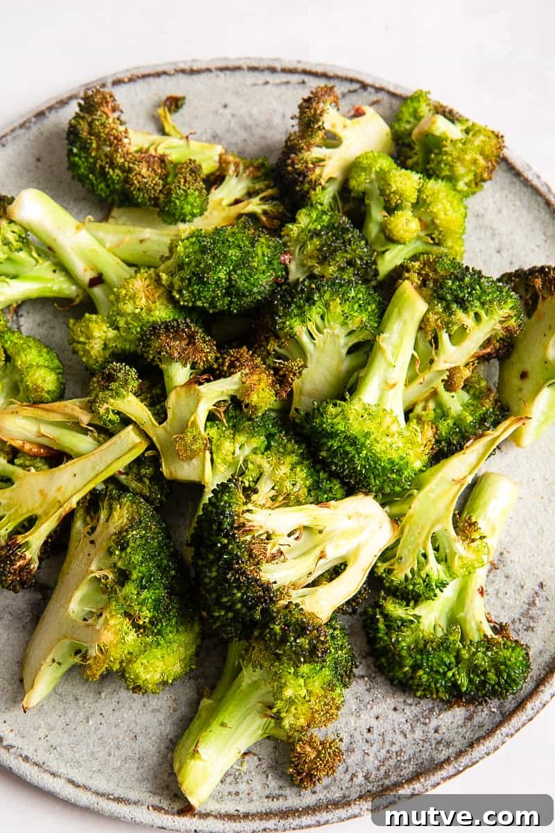 Crispy Air Fryer Broccoli in 10 Minutes 7 Broccoli on on grey plate on white surface.